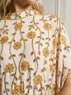 Close-up of the Social Queen Hand-Embellished Floral Caftan Dress in cream chiffon, featuring intricate gold floral beadwork and multicolored accents, worn by a model with long blonde hair.