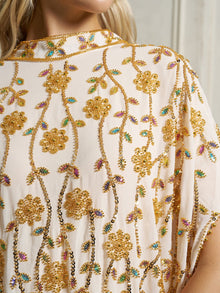 Close-up of the Social Queen Hand-Embellished Floral Caftan Dress in cream chiffon, featuring intricate gold floral beadwork and multicolored accents, worn by a model with long blonde hair.