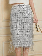 A person wearing the Social Queen Hand-Embellished Sequin Fringe Skirt, holding a small gold clutch bag.