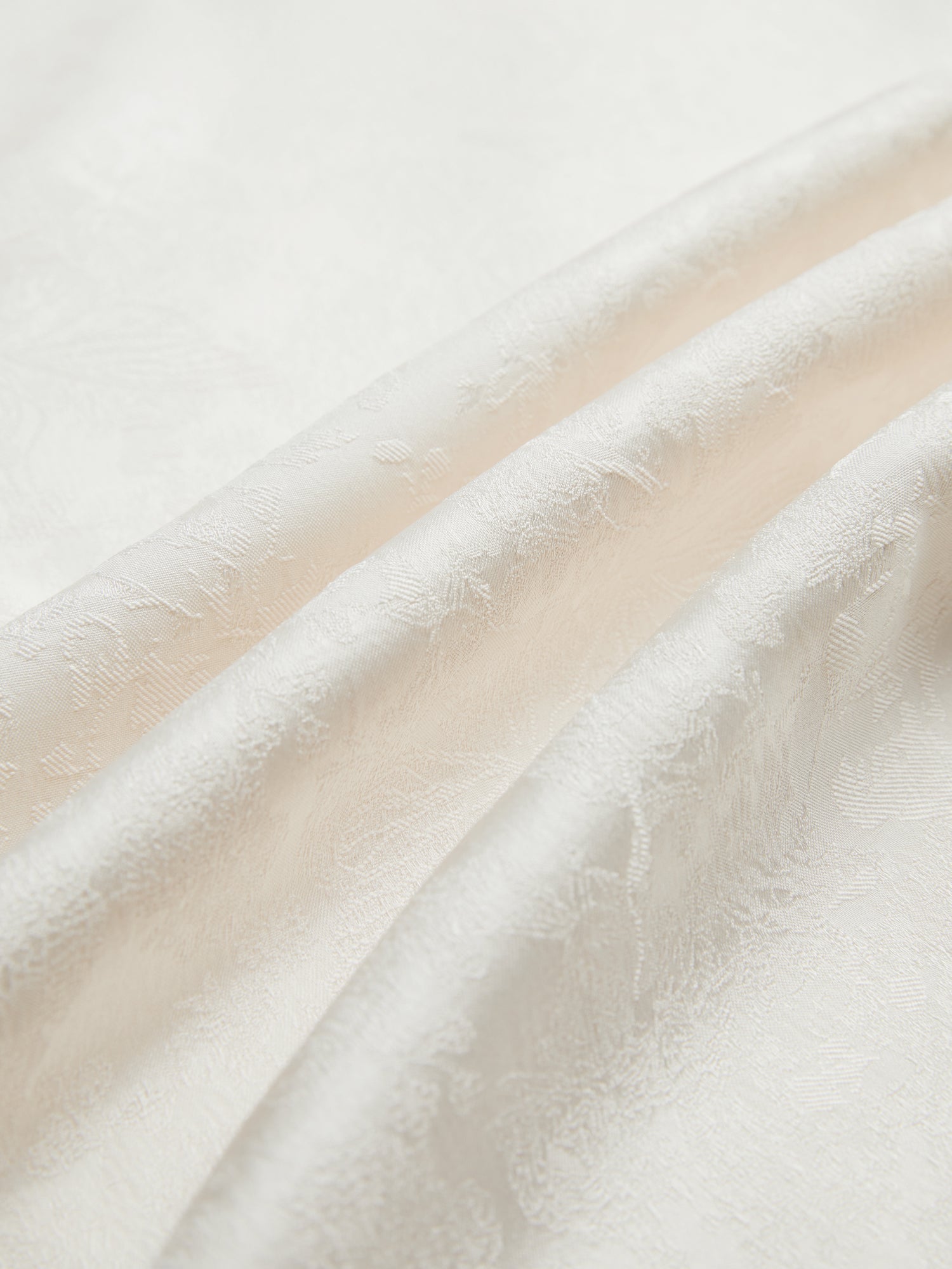 Close-up of the Social Queen Hand-Embroidered Floral Jacquard Pullover, showcasing its white jacquard fabric with subtle floral motifs and soft folds.