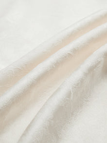 Close-up of the Social Queen Hand-Embroidered Floral Jacquard Pullover, showcasing its white jacquard fabric with subtle floral motifs and soft folds.