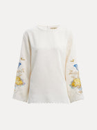 The Social Queen Hand-Embroidered Floral Jacquard Pullover features long sleeves and cream fabric with blue and yellow floral motifs hand-embroidered on the sleeves, shown against a plain white background.