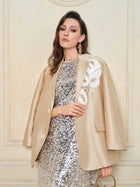 A woman wears the Social Queen Hand-Embroidered Floral Silk-Wool Jacket over a sequined silver dress, standing against a light-colored wall.