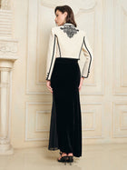 A woman stands indoors facing away, wearing the Social Queen Hand-Embroidered Silk-Wool Cropped Tweed Jacket with a long black skirt, her hair down and styled with black heels.