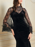 A woman wears the Hand-Sewn Crystal Velvet Feather Mermaid Gown by Social Queen, featuring elegant black velvet, feather details, and a fitted mermaid silhouette.