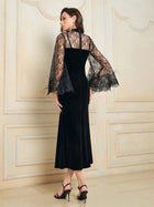 A woman stands indoors wearing the Social Queen Hand-Sewn Crystal Velvet Feather Mermaid Gown and black heeled sandals, facing away from the camera.