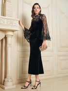 A woman wears the Social Queen Hand-Sewn Crystal Velvet Feather Mermaid Gown, posing indoors with a gold clutch and strappy heels near an ornate fireplace and cream-paneled wall.