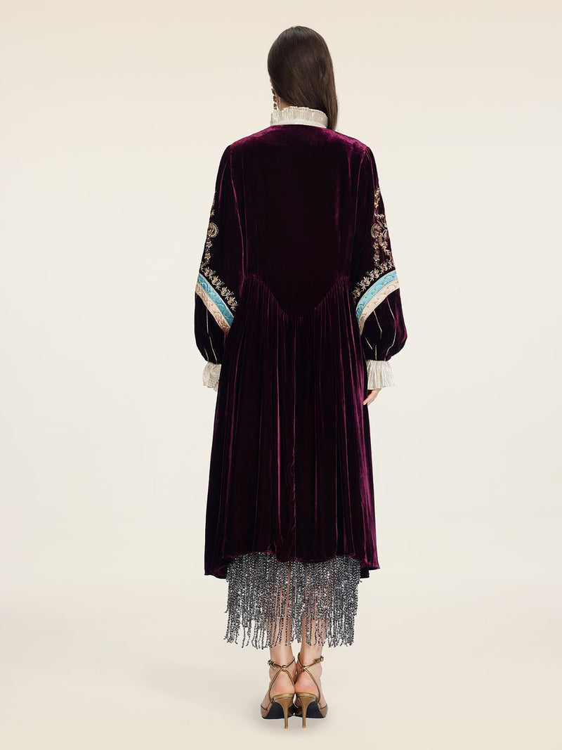 A person faces away, wearing Social Queen’s Handcrafted Embroidered Velvet Jacket with hand-applied pearls, paired with a silver fringe skirt and heels, for a look that channels vintage glamour.
