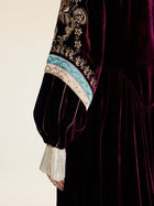 A close-up of a person wearing the Social Queen Handcrafted Embroidered Velvet Jacket, showcasing vintage glamour with ornate gold thread embroidery, blue accents, and hand-applied pearls on the sleeve.