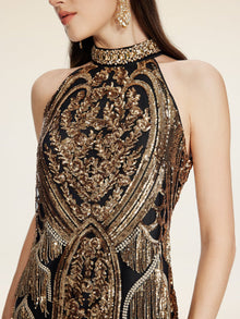 A woman wears the Social Queen Handcrafted Fringe Sequin Halter Gown, a sleeveless black and gold gown with intricate embroidery, sequins, and beaded details, paired with gold earrings.