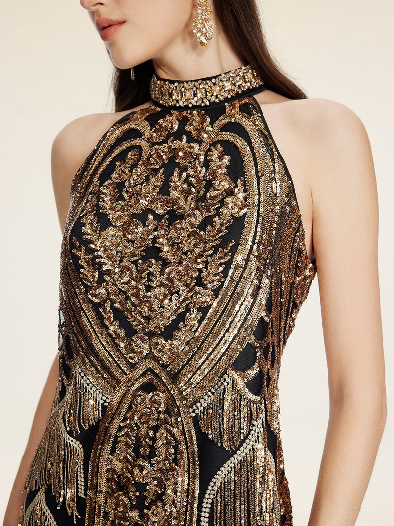 A woman wears the Social Queen Handcrafted Fringe Sequin Halter Gown, a sleeveless black and gold gown with intricate embroidery, sequins, and beaded details, paired with gold earrings.