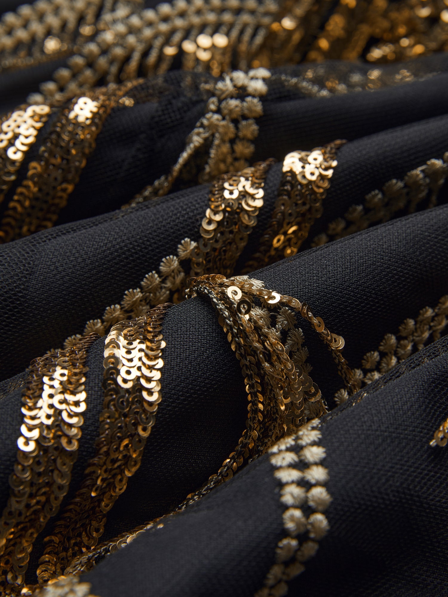 Close-up of black fabric from the Handcrafted Fringe Sequin Halter Gown by Social Queen, featuring hand-applied sequins and beaded embellishments in wavy lines.