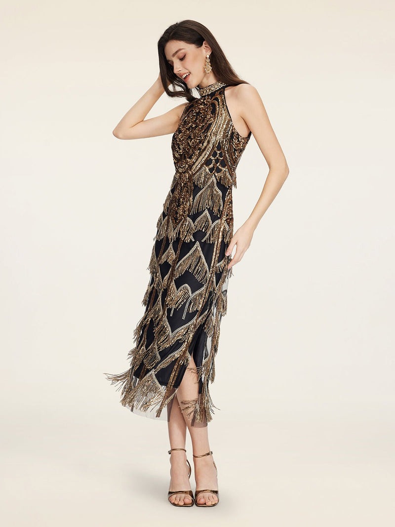 A woman in the Social Queen Handcrafted Fringe Sequin Halter Gown stands with one hand on her head, smiling down. She pairs the black-gold sleeveless dress with high-heeled sandals and earrings.