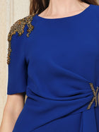 A woman wears the Social Queen Handcrafted Gold-Trimmed Slit Dress, a sapphire midi with short sleeves, gold trims at the shoulders and waist, and a graceful fishtail silhouette.