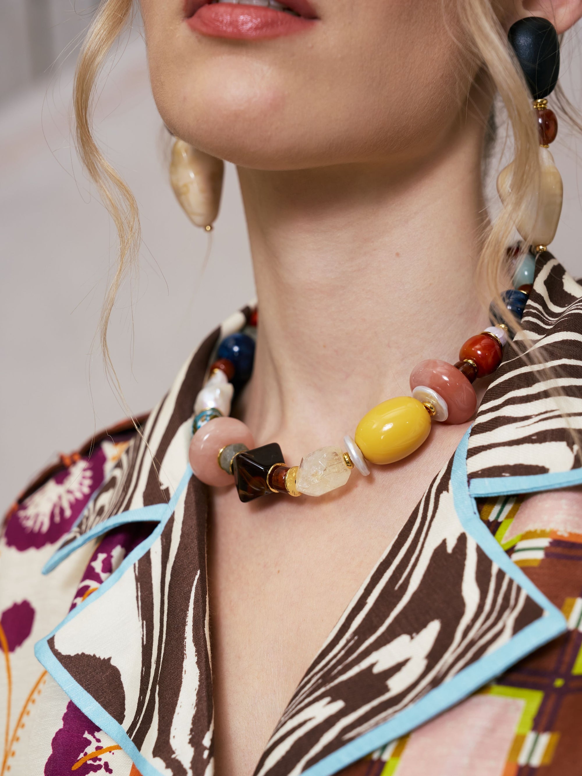 A woman wearing the Social Queen Multicolor Stone Beaded Necklace and a patterned shirt with blue trim, shown from the shoulders up.