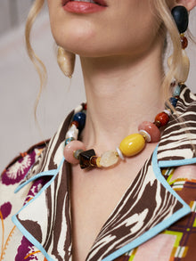 A woman wearing the Social Queen Multicolor Stone Beaded Necklace and a patterned shirt with blue trim, shown from the shoulders up.