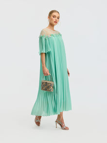 A woman in the Social Queen Floral Embellishment Pleated Dress pairs it with silver heels and a patterned handbag, posing against a plain white background.