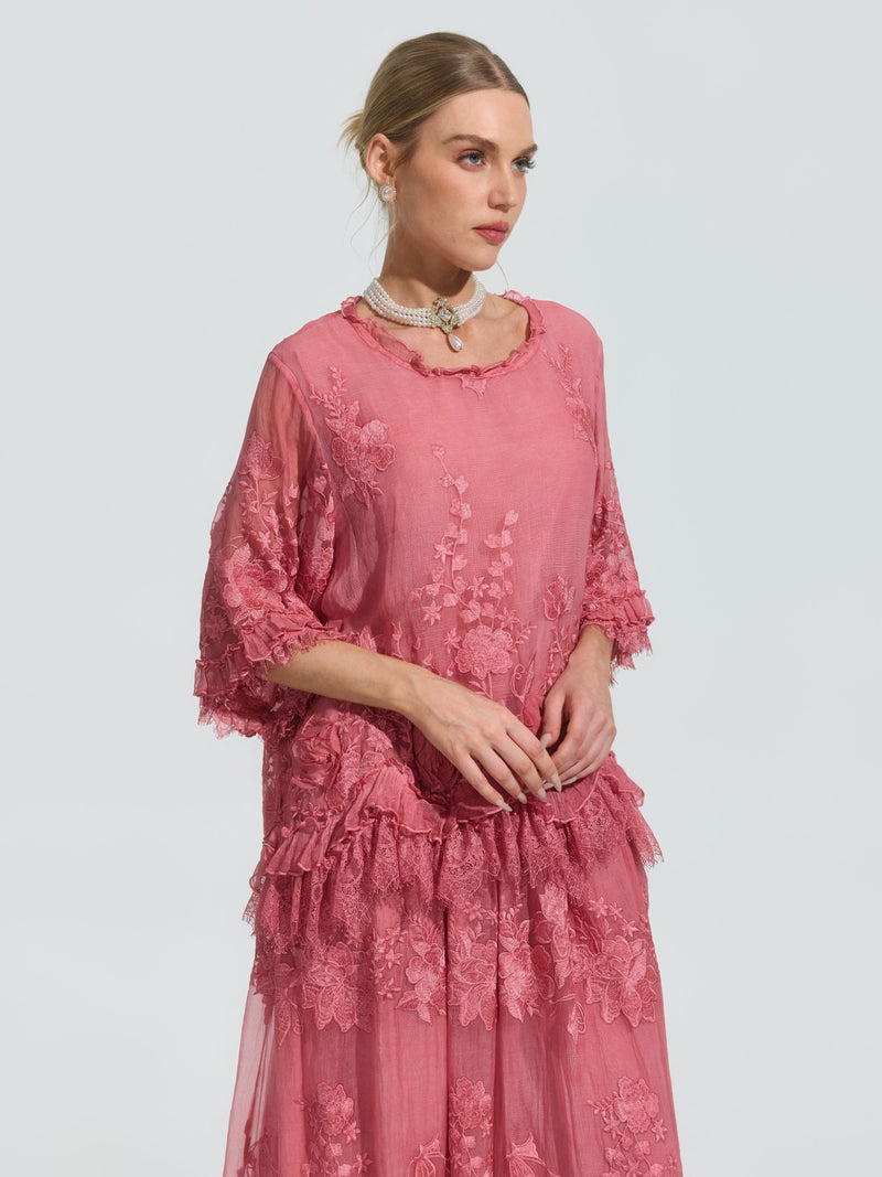 A woman models the Social Queen 3D Floral Embroidered 100% Silk Ruffle Blouse, featuring pink silk, intricate floral embroidery, and delicate ruffles, against a plain light background.