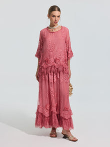 A woman wears the Social Queen 3D Floral Embroidered 100% Silk Ruffle Blouse, featuring floral embroidery and ruffle details, paired with a small purse and sandals against a plain background.