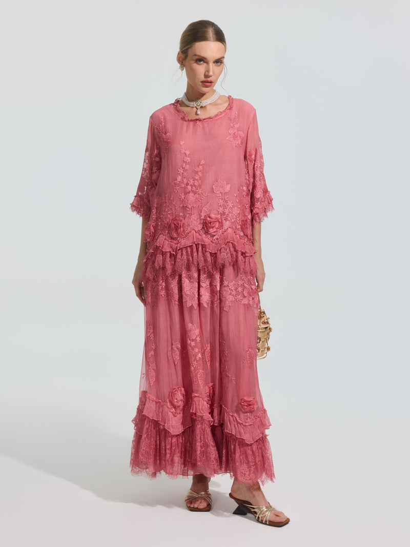 A woman wears the Social Queen 3D Floral Embroidered 100% Silk Ruffle Blouse, featuring floral embroidery and ruffle details, paired with a small purse and sandals against a plain background.