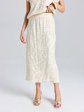 A person models the Social Queen Floral Embroidered Linen Midi Skirt, featuring a cream hue and subtle floral details, styled with open-toe heels against a plain background.