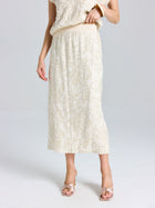 A person models the Social Queen Floral Embroidered Linen Midi Skirt, featuring a cream hue and subtle floral details, styled with open-toe heels against a plain background.