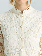 Close-up of a woman wearing the Embroidered Lace High-Neck Dress by Social Queen, featuring cream-colored lace-effect embroidery, decorative buttons, and styled with large textured gold earrings.