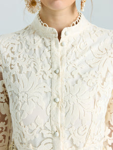 Close-up of a woman wearing the Embroidered Lace High-Neck Dress by Social Queen, featuring cream-colored lace-effect embroidery, decorative buttons, and styled with large textured gold earrings.
