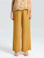 A person shown from chest to feet wears a sleeveless beige top and Social Queen Silk Velvet Wide-Leg Pants in mustard yellow with gold open-toe sandals, posed against a plain background.