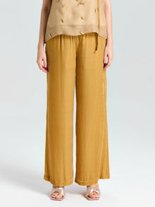 A person shown from chest to feet wears a sleeveless beige top and Social Queen Silk Velvet Wide-Leg Pants in mustard yellow with gold open-toe sandals, posed against a plain background.