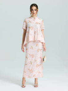 A woman stands facing forward against a plain background, wearing the Social Queen Dragonfly Beaded Lace Top in light pink with delicate embroidery and short sleeves, paired with metallic sandals and holding a small handbag.