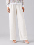 A person wearing Social Queen’s Casual Wide-Leg Pants, featuring a mid-high rise and lyocell-linen blend, paired with open-toe high heels, stands against a plain background, with only the lower half of their body visible.