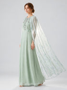 A woman, shown in profile against a plain, light background, wears the Social Queen Beaded Printed Cape Chiffon Dress—a floor-length, lightweight chiffon gown in light green with a sheer, flowing cape.