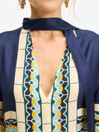 A person wearing the Social Queen Moroccan Print Silk Caftan Dress, featuring navy, yellow, and turquoise geometric patterns, styled with a matching scarf and gold earrings.