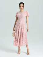 A woman wears the Social Queen Floral Embroidered Lace Dress in light pink, featuring short sleeves and an A-line silhouette, paired with a small handbag and open-toed heels against a plain light background.