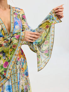 A model showcases the Social Queen Garden Print Silk Maxi Dress, featuring wide, flowing sleeves, against a plain background.