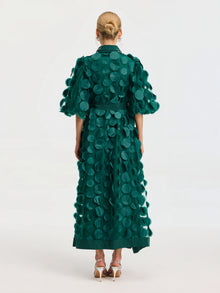 A person wears the Social Queen Pearl Embellished Appliqué Dress in green, ankle-length with large circular appliqués, facing away to show the back of the dress and silver high-heeled sandals.
