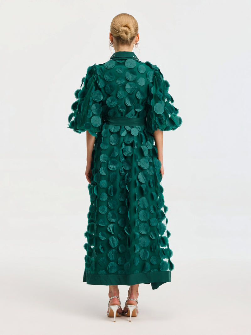 A person wears the Social Queen Pearl Embellished Appliqué Dress in green, ankle-length with large circular appliqués, facing away to show the back of the dress and silver high-heeled sandals.