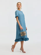 A woman models the Social Queen Beaded Crystal Embellished Dress, featuring a ruffle hem and beaded neckline, paired with a silver handbag, matching heels, and bold earrings.