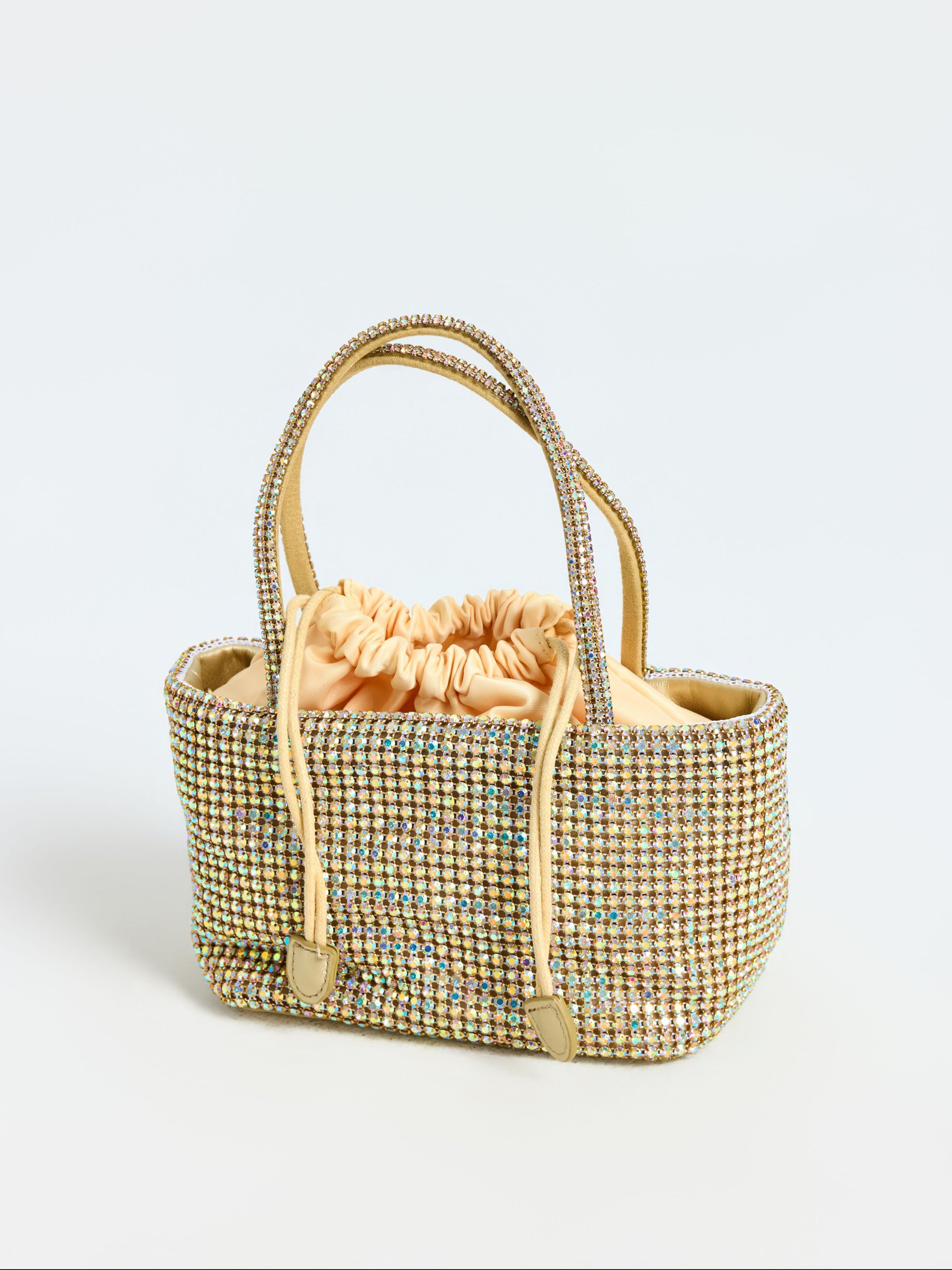 The Social Queen Crystal Embellished Mini Tote Bag features dual handles, an ombré of multicolored rhinestones, and a beige fabric drawstring pouch inside.