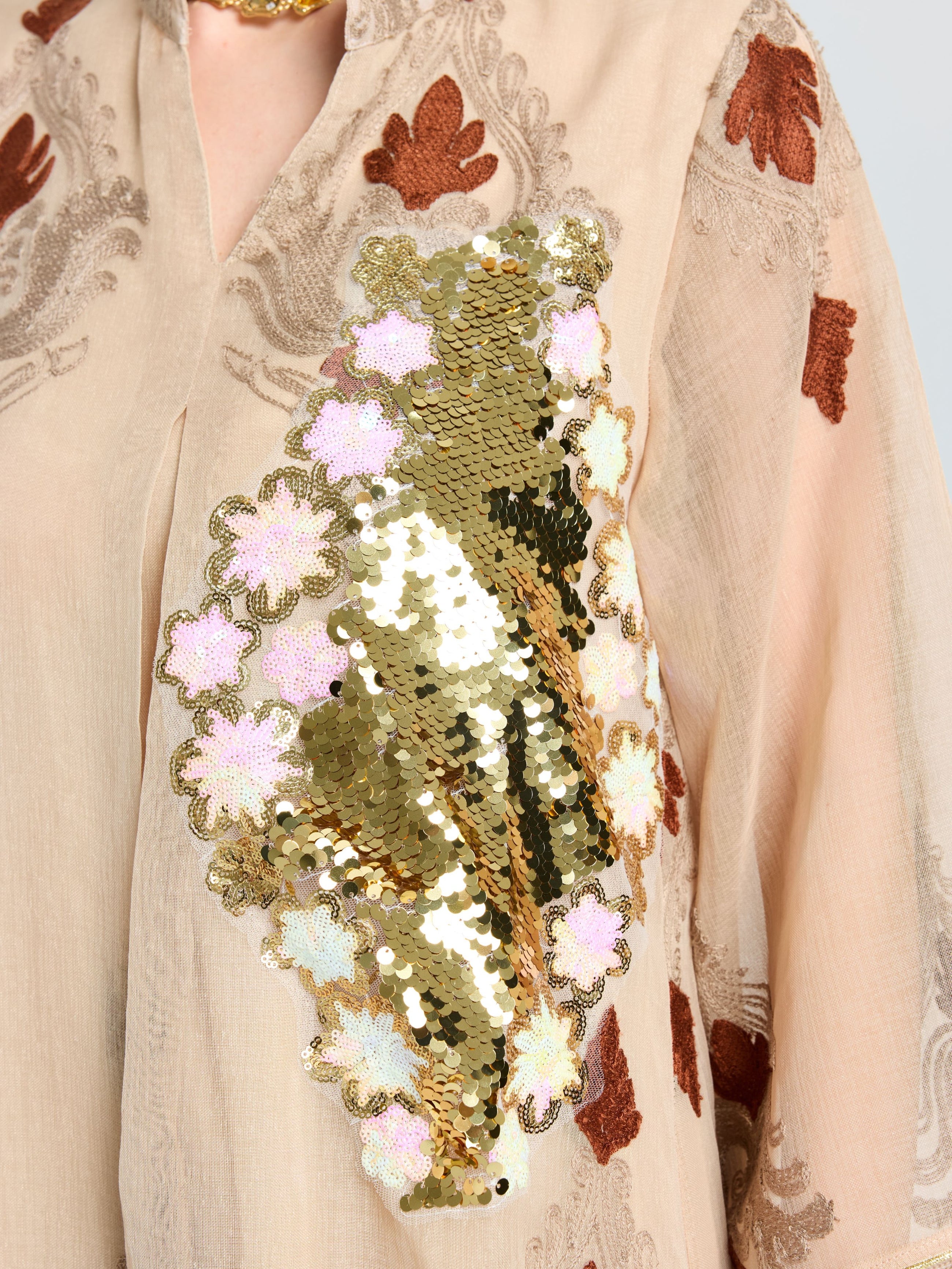 The Social Queen Placement Embroidered Linen Dress is beige with brown embroidered leaves, a damask scroll motif, and a bold gold sequin floral accent on the chest.