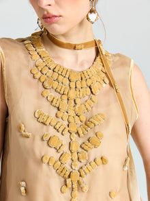 A woman wears the Velvet Scarf Silk Organza Top (Cami Included) by Social Queen, featuring sheer beige silk organza with large golden embellishments, styled with matching choker and earrings.
