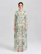 A woman faces forward in the Social Queen Beaded Floral Embellished Cape Gown, a floor-length dress with colorful floral detailing and a high neck, set against a simple light background.