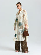A woman models Social Queen’s Floral Embroidered Linen Jacket (Cami Included), styled over brown sequined fringe pants with a matching brown handbag, standing against a plain white background.