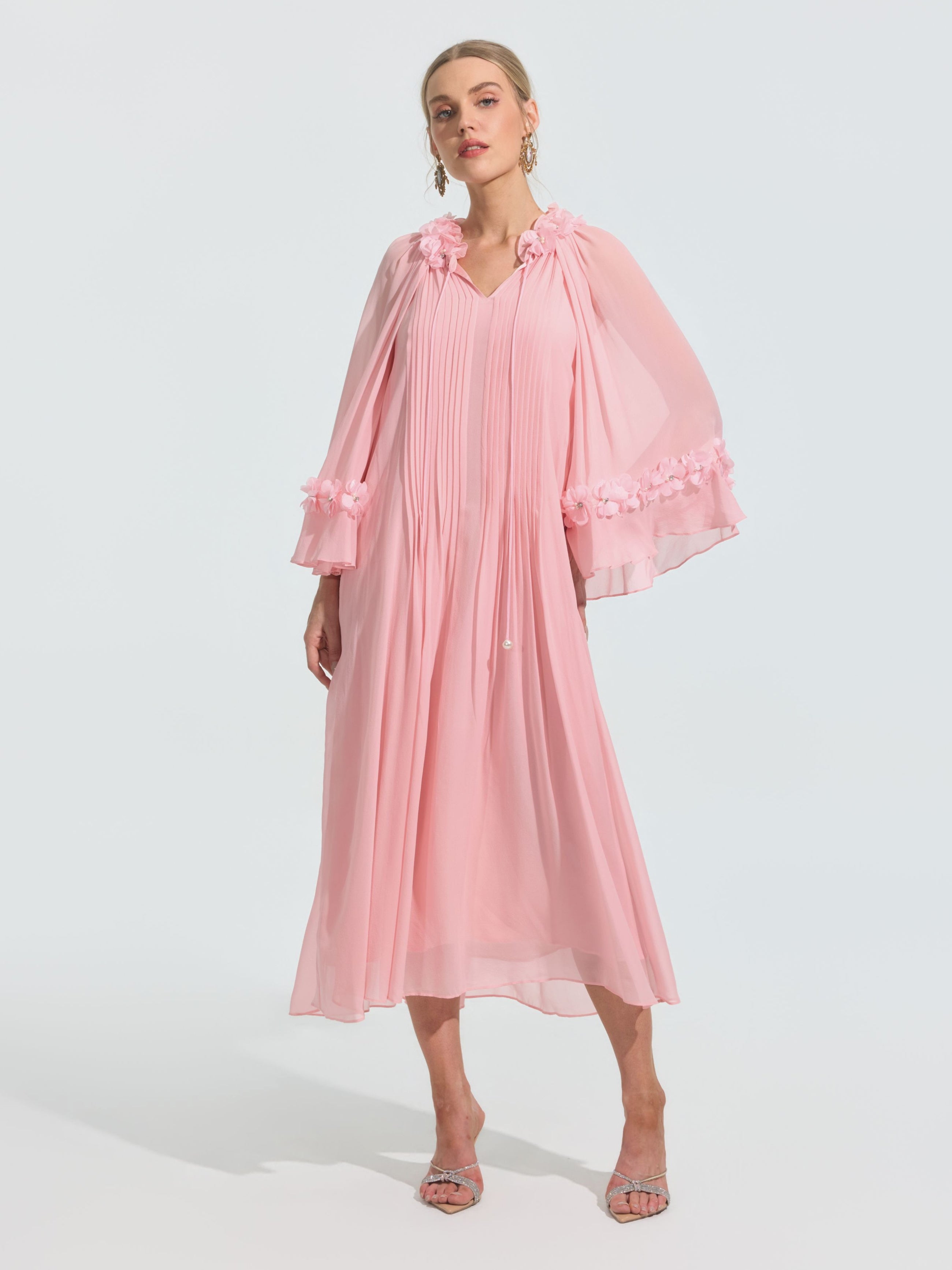 A woman wears the Social Queen 3D Floral Embellished Silk Dress in light pink, featuring long sleeves and 3D floral details on the sleeves and shoulders, paired with open-toe heels against a plain background.