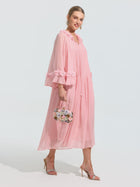 A woman models the Social Queen 3D Floral Embellished Silk Dress—a loose, light pink midi with ruffled sleeves—paired with a small floral handbag and heeled sandals against a plain light background.