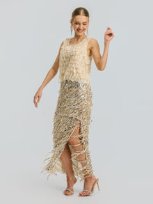 A woman dressed in the Social Queen 3D Leaf Beaded Mesh Top and a silver sequin skirt with a front slit stands in heels against a plain light background.