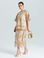 A woman wears the Social Queen Floral Embroidered Lace Top with elbow-length sleeves and a beaded neckline, paired with heeled sandals and a gold handbag, standing against a plain background.