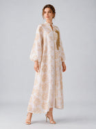 A woman wearing the Social Queen Leaf Embroidered Beaded Dress—with long sleeves and delicate beaded leaf embroidery—paired with heeled sandals, stands against a light gray background.