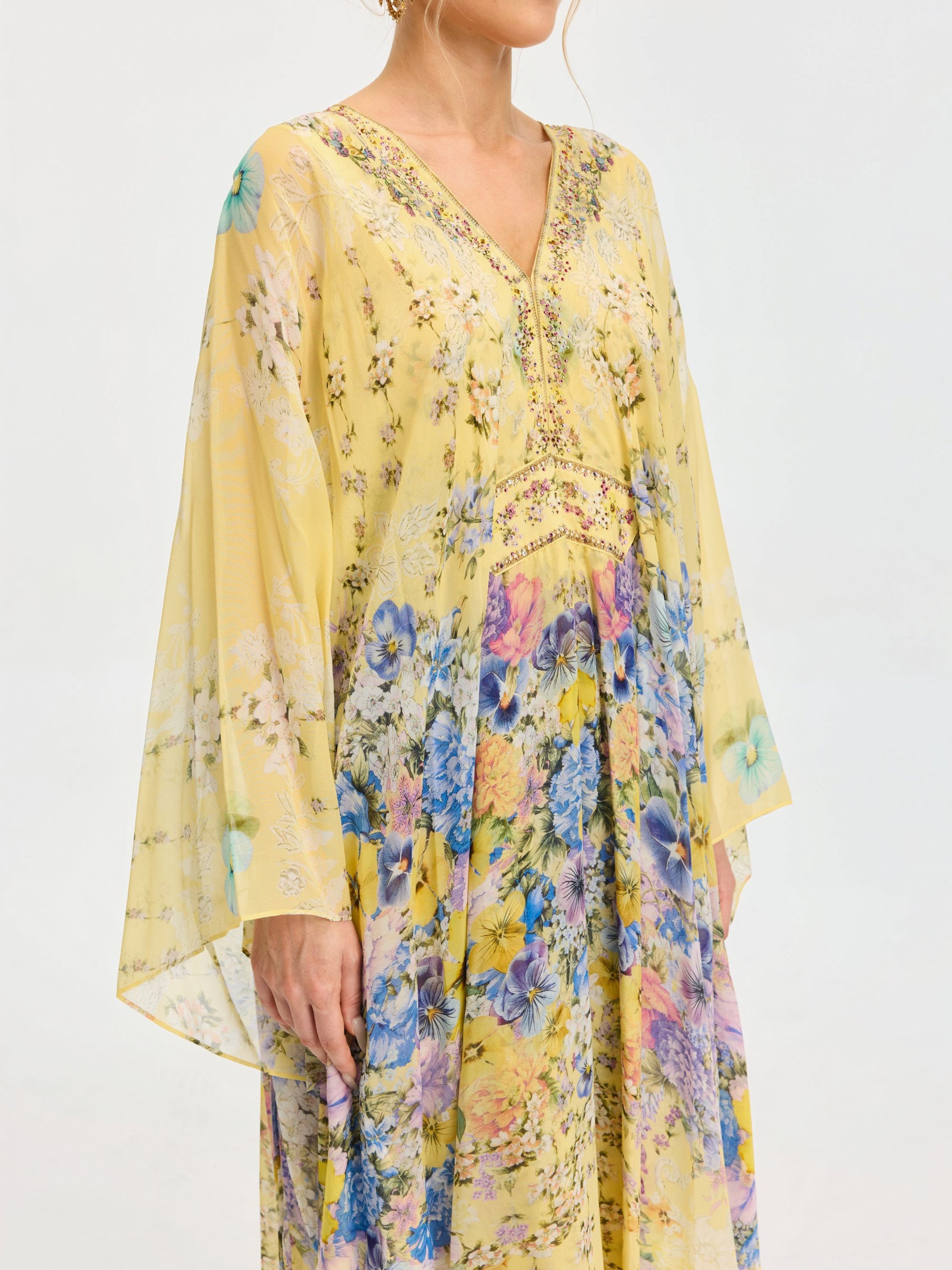 A woman wearing the Social Queen Floral Print Silk Caftan Dress—yellow, long-sleeved, V-neck and perfect for resort wear—stands against a plain background.